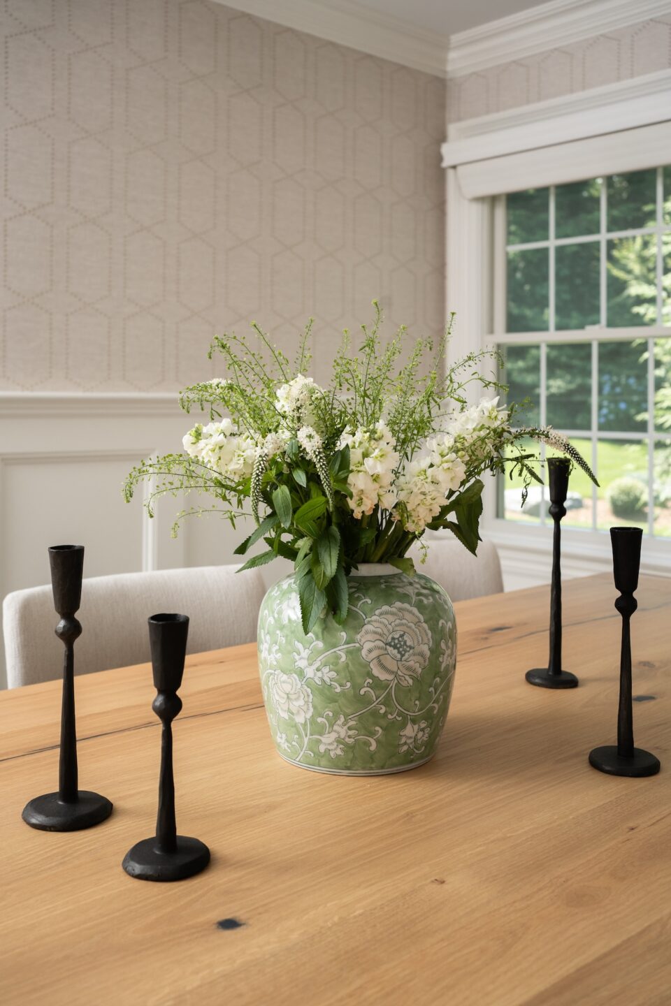 Light Wood Dining Table With Vase Of Green White Flowers
